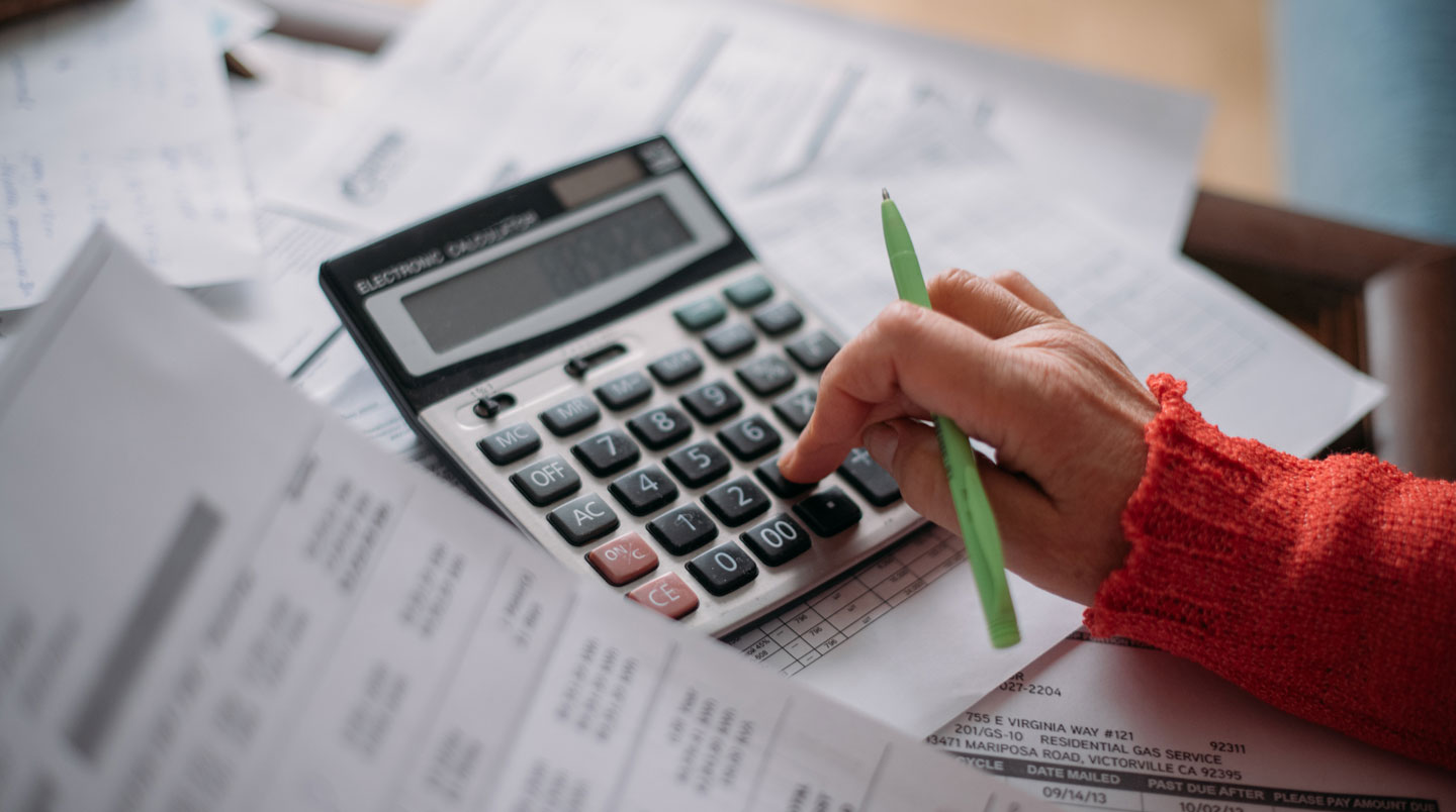 Vue de dessus d'un bureau épuré avec documents financiers en français étalés : contrat de leasing, feuille de calcul TCO manuscrite, facture d'électricité, carte bancaire et smartphone affichant une application budgétaire